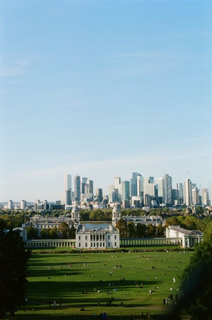 Exterior view of a historic white stone building with a large central dome topped by a golden finial, featuring classical architectural elements such as columns, arched windows, and decorative statues